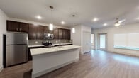 This single-floor residence showcases a thoughtfully designed open-concept layout with modern finishes throughout. The kitchen serves as a central highlight, featuring rich dark espresso cabinetry, crisp white quartz countertops, a large island with an undermount sink, and a full suite of stainless steel appliances. Gray subway tile backsplash and pendant lighting add a contemporary touch, while wood-look luxury vinyl plank flooring flows seamlessly through the main living areas. The bedrooms are carpeted for comfort and feature neutral tones, with one offering dual windows and a ceiling fan for added comfort. Closet space is generously provided, including a large walk-in closet outfitted with built-in shelving, hanging rods, and dedicated shoe storage, as well as additional reach-in closets with double hanging rods. The bathrooms are finished with dark vanity cabinetry, white countertops, and wood-look flooring. One bathroom features a tiled walk-in shower with glass enclosure, while another includes a soaking tub with tile surround. Open shelving provides practical storage. The overall aesthetic is clean, contemporary, and move-in ready.