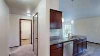 Located in East Wenatchee, WA, this well-appointed 2-bedroom, 2-bathroom single-floor home offers a functional and comfortable layout. The kitchen is a standout feature, showcasing rich dark wood cabinetry, granite countertops, stainless steel appliances including an electric range, microwave, and refrigerator, along with a peninsula with pendant lighting and a built-in sink. Hardwood flooring runs throughout the kitchen and main areas, lending warmth and continuity to the space. The spacious primary bedroom is carpeted and features a wall-mounted HVAC unit, a ceiling light fixture, and a window with views of the surrounding neighborhood. The second bedroom is similarly carpeted with a bright window and generous proportions. Both bathrooms are clean and practical, each equipped with a full tub-shower combination with brushed nickel fixtures. A dedicated laundry room houses a full-size washer and dryer with overhead shelving for added storage. A hallway connects the main living areas to the private quarters, and a closet provides additional storage. The home's overall design emphasizes functionality and comfort with a neutral color palette and quality finishes throughout.