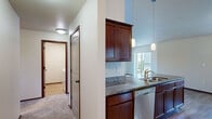 Located in East Wenatchee, WA, this well-appointed 2-bedroom, 2-bathroom single-floor home offers a functional and comfortable layout. The kitchen is a standout feature, showcasing rich dark wood cabinetry, granite countertops, stainless steel appliances including an electric range, microwave, and refrigerator, along with a peninsula with pendant lighting and a built-in sink. Hardwood flooring runs throughout the kitchen and main areas, lending warmth and continuity to the space. The spacious primary bedroom is carpeted and features a wall-mounted HVAC unit, a ceiling light fixture, and a window with views of the surrounding neighborhood. The second bedroom is similarly carpeted with a bright window and generous proportions. Both bathrooms are clean and practical, each equipped with a full tub-shower combination with brushed nickel fixtures. A dedicated laundry room houses a full-size washer and dryer with overhead shelving for added storage. A hallway connects the main living areas to the private quarters, and a closet provides additional storage. The home's overall design emphasizes functionality and comfort with a neutral color palette and quality finishes throughout.