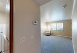 Located at 115 Louie Ave in Lodi, California, this one-bedroom, one-bathroom unit offers a well-organized single-floor layout that makes efficient use of its intimate square footage. The living area is finished with plush gray carpeting and features crown molding along the ceiling, warm neutral-toned walls, and a window fitted with blinds that allows natural light to filter in while maintaining privacy. A programmable thermostat is conveniently situated in the hallway, providing easy climate control throughout the home. The bedroom is a comfortable size, also carpeted, and is equipped with a mirrored sliding-door closet that includes built-in shelving and a hanging rod for ample storage. A sliding glass door leads directly from the bedroom to a private balcony, offering outdoor access and views of the surrounding area. The galley-style kitchen features warm wood cabinetry, white appliances including a range and refrigerator, light wood-look vinyl flooring, and generous counter space on both sides — a practical and efficient workspace. Crown molding details carry throughout the living spaces, lending a cohesive, finished look to the interior. The bathroom and hallway round out the functional floor plan, making this a well-appointed unit suited for comfortable everyday living in the heart of Lodi.