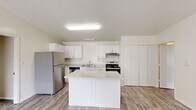 This single-story, 3-bedroom, 2-bathroom home offers an efficient and well-organized layout designed for comfortable everyday living. The kitchen serves as a central hub of the home, featuring white cabinetry, stainless steel appliances including a refrigerator, dishwasher, and range, and a white island that provides additional workspace and storage. Wood-look flooring in the kitchen and living areas creates a cohesive, easy-to-maintain foundation, while a large window floods the open living space with natural light.

The three bedrooms are each carpeted for comfort and equipped with ceiling fans for climate control. Each room includes a closet with built-in shelving, offering practical storage solutions. Windows with blinds allow for natural light while maintaining privacy, and wall-mounted HVAC units provide individual climate control.

The two bathrooms are finished in a clean, neutral palette. One features a full tub-and-shower combination with wood-look flooring and a vanity, while the second is a more compact three-quarter bath. Both bathrooms are appointed with chrome fixtures and light-toned walls for a bright, tidy feel. Overall, the home presents a straightforward, functional design with consistent neutral tones throughout.