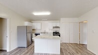 This single-story, 3-bedroom, 2-bathroom home offers an efficient and well-organized layout designed for comfortable everyday living. The kitchen serves as a central hub of the home, featuring white cabinetry, stainless steel appliances including a refrigerator, dishwasher, and range, and a white island that provides additional workspace and storage. Wood-look flooring in the kitchen and living areas creates a cohesive, easy-to-maintain foundation, while a large window floods the open living space with natural light.

The three bedrooms are each carpeted for comfort and equipped with ceiling fans for climate control. Each room includes a closet with built-in shelving, offering practical storage solutions. Windows with blinds allow for natural light while maintaining privacy, and wall-mounted HVAC units provide individual climate control.

The two bathrooms are finished in a clean, neutral palette. One features a full tub-and-shower combination with wood-look flooring and a vanity, while the second is a more compact three-quarter bath. Both bathrooms are appointed with chrome fixtures and light-toned walls for a bright, tidy feel. Overall, the home presents a straightforward, functional design with consistent neutral tones throughout.