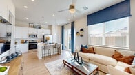 Located on N Elm St in Denton, TX, this single-story 2-bedroom, 3-bathroom home offers a thoughtfully designed open-concept layout with light wood-style flooring throughout. The living room is bright and welcoming, featuring a ceiling fan, large windows with bold navy accents, and a sliding glass door that connects to the outdoors. Adjacent to the living area, the kitchen is a standout feature with crisp white shaker cabinetry extending to the ceiling, a white subway tile backsplash, quartz countertops, stainless steel appliances, and a central island with bar seating and pendant lighting — ideal for both cooking and entertaining. A connecting hallway with recessed lighting leads to the two bedrooms, each offering natural light, ceiling fans, and ample closet space. The primary bedroom includes an en-suite bathroom with a walk-in glass-enclosed shower and tile surround. The second bedroom is generously sized and bright. Three bathrooms in total serve the home comfortably. A dedicated laundry area adds convenience. Outside, the private backyard features a wood privacy fence with greenery accents, a gravel border, and a patch of turf — a low-maintenance outdoor retreat.