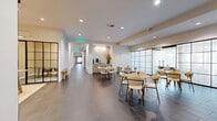 Located at 75 Tresser Blvd in downtown Stamford, CT, this thoughtfully designed amenity floor offers a generous and versatile layout across a single, expansive level. The space blends contemporary aesthetics with practical functionality, catering to a wide range of needs.

The dining room serves as an elegant gathering space, anchored by a large white table surrounded by classic wooden armchairs and illuminated by a striking oversized pendant light. Warm taupe walls, textured cabinetry, and soft carpeting create a refined yet welcoming atmosphere.

A collaborative work lounge features a long communal table with bar-height seating, set beneath sleek gold-toned linear pendant lighting. Steel-framed glass partitions enclose private work pods along the perimeter, offering focused workspaces within an open, airy environment. Large-format dark tile flooring grounds the space.

The living room provides a relaxed retreat with plush modular seating, soft carpeting, and floor-to-ceiling drapery that can section off areas for privacy. Clerestory windows bring in natural light.

A bright children's area is clad in warm wood paneling, featuring built-in shelving with arched niches, abundant natural light from oversized windows, and durable hardwood flooring. The laundry room is outfitted with granite countertops, white cabinetry, and stainless steel appliances. Well-connected hallways tie the entire floor together seamlessly.