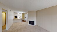 This single-floor residence offers a functional and comfortable layout designed for everyday living. The open-concept living area serves as the heart of the space, featuring neutral-toned carpet, a textured ceiling, and a tile-hearth fireplace with a classic black surround — an inviting focal point for the room. The layout flows naturally toward the kitchen, which is accessed via a breakfast bar-style peninsula. The kitchen is well-appointed with warm wood cabinetry, granite-look countertops, and a full suite of stainless steel appliances including a range, microwave, and dishwasher, complemented by wood-style flooring.

The bedrooms are generously sized, each finished with plush carpeting and natural light provided by windows with blinds. Multiple bedrooms include built-in closets, offering practical storage solutions. One bedroom features a walk-in-style closet with a rod system for organized storage.

The bathroom is clean and functional, featuring a full tub-shower combination, a vanity with a stone-look countertop, a wood-toned cabinet base, and wood-style flooring. Throughout the unit, a consistent warm, neutral color palette creates a cohesive and move-in-ready atmosphere.