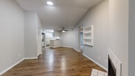 This single-floor residence offers a thoughtfully designed layout that balances open communal spaces with comfortable private areas. The living room serves as the centerpiece of the home, showcasing vaulted ceilings that amplify the sense of space, warm hardwood-style flooring, a ceiling fan, and a tile-surround fireplace. A large sliding glass door floods the room with natural light and provides outdoor access. Built-in wall shelving adds both character and functional storage to the living area.

The kitchen is designed for practicality, featuring white cabinetry, light countertops, a double stainless steel sink beneath a window overlooking greenery, and a peninsula that connects to the main living space. Appliances include a dishwasher, electric range, and an over-the-range microwave.

A hallway with hardwood-style flooring connects the living areas to the bedrooms. The bedrooms feature plush carpeting and closets with paneled doors. Two bathrooms serve the home: one includes a tub-shower combination with white tile accented by a gray border stripe and a white vanity, while the second features a glass-enclosed walk-in shower with matching tile detailing and a white vanity. Both bathrooms continue the hardwood-style flooring found throughout the rest of the home.