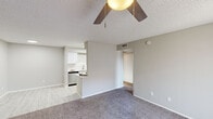 Located at 5215 West Peoria Avenue in Glendale, Arizona, this one-bedroom, one-bathroom unit offers a well-organized single-floor layout designed for comfortable everyday living. The combined kitchen and living area forms the heart of the home, where light vinyl plank flooring runs through the kitchen while plush carpet extends into the living space. A ceiling fan with built-in lighting keeps the area comfortable year-round. The kitchen is galley-style, outfitted with white cabinetry, white countertops, a subway tile backsplash, stainless steel appliances including a range, microwave, and dishwasher, and a skylight that draws in additional natural light. A peninsula provides a convenient transition between the kitchen and living room. The living area features a sliding glass door dressed with vertical blinds, offering outdoor views and filling the room with natural light. The bedroom is a well-proportioned retreat finished with soft carpet, neutral gray walls, a textured ceiling, and a window with blinds that overlooks greenery outside. A dedicated closet provides practical storage. The bathroom is clean and functional, featuring a full-size soaking tub with shower combination. A hallway connects the spaces efficiently, completing this thoughtfully laid-out home.