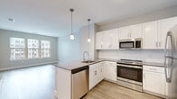 Located at 4 Tuscan Blvd in Salem, New Hampshire, this single-floor residence offers a thoughtfully designed layout with a clean, modern aesthetic. The open-concept kitchen serves as the heart of the home, featuring crisp white shaker cabinetry, a classic subway tile backsplash, and a peninsula with a built-in sink and pendant lighting overhead. Stainless steel appliances — including a refrigerator, range, microwave, and dishwasher — complement the smooth gray quartz-style countertops, while light wood-tone luxury vinyl flooring runs seamlessly throughout the main living areas, creating a warm, cohesive feel. The living area is spacious and open, bathed in natural light from well-placed windows, with neutral gray walls that provide a versatile backdrop. The bedrooms offer plush wall-to-wall carpeting, generous wall space, and easy access to closet storage, delivering a quiet and comfortable retreat. The bathroom is finished with large-format neutral floor tile, a single vanity with a stone-topped sink, a full soaking tub with tiled surround, and a lit mirror, maintaining the home's clean and functional design language. Throughout the space, consistent white trim, recessed lighting, and a soft neutral color palette contribute to a bright, move-in-ready environment.