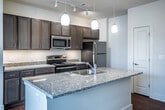 This single-floor, two-bedroom, two-bathroom residence in Memphis, TN offers a well-designed layout with a clear separation between living and sleeping areas. The open-concept kitchen serves as a central feature, anchored by a large granite-topped island with an integrated sink and pendant lighting overhead. Dark espresso cabinetry pairs with stainless steel appliances — including a refrigerator, electric range, microwave, and dishwasher — and track lighting completes the functional, modern aesthetic. Hardwood-style flooring flows throughout the kitchen and main living areas, adding warmth and visual continuity.

Both bedrooms are generously proportioned, carpeted for comfort, and equipped with ceiling fans. Multiple windows in each room allow for ample natural light. The primary bathroom features a granite-topped double vanity with dark cabinetry, hardwood-style flooring, a soaking tub, and direct access to a walk-in closet. The second bathroom offers a single vanity with matching granite counters and hardwood-style flooring. Neutral wall tones and clean finishes throughout contribute to a cohesive, move-in-ready ambiance.