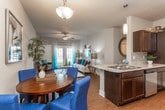 This single-story residence is thoughtfully designed with an open-concept layout that seamlessly connects the living, dining, and kitchen areas. The living room is a welcoming space highlighted by vaulted ceilings, a ceiling fan, and wood-style flooring. French doors open to a private balcony, allowing natural light to fill the room. The kitchen features dark espresso cabinetry, granite-style countertops, a subway tile backsplash, and stainless steel appliances including a refrigerator, range, microwave, and dishwasher. A breakfast bar provides additional seating and connects the kitchen to the dining area.

The primary bedroom is generously sized with plush carpeting, a ceiling fan, multiple windows, and ample closet space. A secondary bedroom offers similar comfort with ceiling fan and closet access. Both bathrooms are finished with dark wood cabinetry, granite countertops, and tiled tub-shower combinations, with the primary bath featuring a dual-sink vanity. A dedicated laundry area accommodates a full-size washer and dryer, adding everyday convenience to this well-rounded residence.