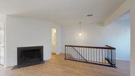 This thoughtfully designed space offers a seamless blend of modern finishes and classic architectural details across a well-organized floor plan. The open living area is a standout feature, showcasing light hardwood flooring, crisp white walls, and a striking fireplace set into a curved wall that serves as a natural focal point. An iron and wood staircase railing adds a refined industrial touch, while a distinctive oval accent window and pendant lighting contribute to the space's character and charm.

The kitchen is well-equipped and stylish, featuring gray shaker-style cabinetry, dark granite countertops, stainless steel appliances including a refrigerator, range, and microwave, and a peninsula with pendant lighting overhead. Light hardwood floors continue throughout, tying the kitchen seamlessly to the main living area. A sliding glass door in the adjacent dining area allows natural light to pour in.

The bedrooms are comfortable and generously sized, finished with neutral carpet, ample closet space, and windows that bring in natural light. The bathrooms maintain the clean aesthetic of the rest of the space, with white fixtures, a simple vanity, and light flooring. Overall, the space presents a clean, move-in-ready environment with a cohesive and contemporary design sensibility throughout.