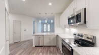 This thoughtfully designed single-floor residence offers a cohesive, modern aesthetic throughout its efficiently utilized layout. The open-concept kitchen and living area form the heart of the home, anchored by durable wood-look flooring that flows seamlessly between spaces. The kitchen is a standout feature, boasting white shaker-style cabinetry, granite countertops, a subway tile backsplash, and a full suite of stainless steel appliances including an electric range, over-the-range microwave, dishwasher, and side-by-side refrigerator. A peninsula with an undermount sink and pendant lighting above adds both function and style, opening directly to the living area. The living room benefits from a ceiling fan and French doors that invite natural light and provide outdoor access. The bedroom is finished with plush carpeting, a ceiling fan, a natural light window, and access to a dedicated closet with built-in shelving. The full bathroom features a granite-topped vanity, white cabinetry, wood-look tile flooring, and a combination tub and glass-enclosed shower. Connecting hallways and a closet complete the functional layout of this clean, contemporary residence.