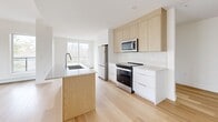 This thoughtfully designed two-bedroom, three-bathroom unit in East Hants, Nova Scotia offers a clean, contemporary aesthetic across a single well-organized floor. Light-toned hardwood flooring flows throughout, lending warmth and continuity to the open-concept living space. Large windows in the living area and kitchen flood the interior with natural light and frame peaceful treetop views, creating a bright and airy atmosphere.

The kitchen is a standout feature, showcasing a combination of white lower cabinetry and natural wood upper cabinets, complemented by a matching island with an integrated sink, stone countertops, a subway tile backsplash, and a full suite of stainless steel appliances. The living room is generously proportioned, with a wall-mounted mini-split unit providing efficient climate control alongside baseboard heating.

The primary bedroom is well-sized and includes a built-in closet with shelving, while the second bedroom is equally bright with clean white walls and hardwood flooring. Three bathrooms serve the unit, at least one featuring a soaker tub with a glass panel enclosure and crisp white tile surround. A hallway connects the private areas of the home, with in-unit laundry accessible nearby. The overall design is minimal, modern, and move-in ready.