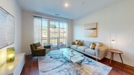 Located at 705 Broadway St in Seneca, South Carolina, this single-floor residence combines modern design with functional living spaces throughout. Rich hardwood-style flooring runs consistently across the entire unit, creating a cohesive and polished aesthetic.

The open-concept kitchen is a standout feature, showcasing dark espresso cabinetry, white quartz countertops, a subway tile backsplash, and black appliances. A large island with seating for multiple guests serves as both a practical workspace and a central gathering point, illuminated by elegant pendant lighting overhead.

The living area is bright and airy, benefiting from large sliding glass doors that open to an outdoor balcony, flooding the space with natural light and providing pleasant exterior views. The room comfortably accommodates a full seating arrangement, anchored by a statement area rug.

The bedrooms are well-sized, each featuring multiple windows that invite natural light, ceiling fans, and ample room for furnishings. The primary bedroom connects directly to a private bathroom outfitted with dark wood vanity cabinetry, a white quartz countertop, a large mirror, and a walk-in closet with built-in wire shelving for generous storage. A second bathroom mirrors the same refined finishes found throughout the home, maintaining design consistency across the space.