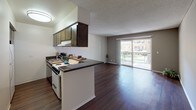 Located at 200 City Blvd W in Orange, California, this single-floor residence offers a thoughtfully designed open-concept layout that seamlessly connects the kitchen and living areas. Rich, dark hardwood flooring flows throughout the main living space, lending warmth and a polished aesthetic to the interior.

The kitchen is positioned along a peninsula-style counter with dark granite countertops and warm wood cabinetry overhead, providing ample storage and prep space. It opens directly into the spacious living area, making it ideal for entertaining or everyday living. A textured ceiling adds a classic finishing touch throughout.

Large sliding glass doors in the living area lead to a private balcony, where a railing overlooks a well-maintained, tree-lined courtyard—bringing natural light deep into the interior and offering a pleasant outdoor retreat.

The bathroom is well-appointed with granite countertops, a white under-mount sink, white cabinetry, and dual medicine cabinet mirrors. A separate enclosed shower and a closet with built-in shelving round out the functional layout.

Overall, the space presents a clean, comfortable living environment with practical finishes, an abundance of natural light, and a serene connection to the landscaped surroundings of the Orange, CA community.