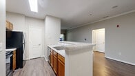 This well-appointed 2-bedroom, 1-bathroom residence on Lottsford Road in Upper Marlboro, Maryland offers a thoughtfully designed single-floor layout. The open-concept living and kitchen area serves as the heart of the home, where rich hardwood-style flooring flows throughout. A classic white-mantled fireplace anchors the living room, adding warmth and character. The kitchen features warm oak cabinetry, light granite-style countertops, black appliances including a refrigerator and microwave, and a raised breakfast bar that connects seamlessly to the living space. Crown molding in the main living area adds an elegant finishing touch. The spacious primary bedroom offers ample room, with dual windows providing generous natural light and outdoor views of the lush surroundings. The second bedroom is also well-sized, with its own window for natural light. Both bedrooms feature the same hardwood-style flooring found throughout the home. The full bathroom is clean and functional, equipped with a tiled tub-shower combination. A hallway connects the main living areas to the bedrooms, and two dedicated closets provide practical storage solutions. Neutral gray tones throughout create a calm, move-in-ready ambiance.