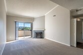 Located in Laguna Niguel, CA, this one-bedroom, one-bathroom residence offers a well-designed single-floor layout with thoughtful architectural details throughout. The spacious living room is a standout, featuring soaring vaulted ceilings with crown molding, a textured ceiling, plush wall-to-wall carpeting, and a tile-surround fireplace. Sliding glass doors open to a private balcony that captures sweeping outdoor views, flooding the room with natural light. The kitchen is efficiently laid out with white shaker cabinetry, dark countertops, stainless steel appliances including a refrigerator, range, microwave, and dishwasher, and hardwood-style flooring paired with a bright window overlooking greenery. The bedroom is generously proportioned with impressively tall ceilings, soft carpeting, a closet, and a window framing scenic treetop and hillside views. The bathroom features a single-sink vanity with a dark wood-tone countertop, a tub/shower combo with white surround, and a high window for natural light. A welcoming entryway with crown molding and recessed lighting completes this well-appointed Laguna Niguel residence.