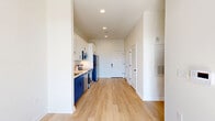 Located at 225 W Olney Rd in Norfolk, VA, this thoughtfully designed one-bedroom, one-bathroom unit offers a efficient and modern living experience across a single floor. The open-concept layout connects the kitchen and living area, creating a seamless flow throughout the space. Light-toned hardwood-style flooring runs throughout the main areas, complementing the bright, neutral walls and recessed lighting overhead.

The kitchen is a standout feature, showcasing a two-tone design with crisp white upper cabinetry and bold navy blue lower cabinets, paired with white quartz countertops and a classic subway tile backsplash. Stainless steel appliances — including a refrigerator, electric range, microwave, and dishwasher — complete the modern aesthetic. A pantry provides additional storage convenience.

The living area opens to a private balcony through large floor-to-ceiling sliding glass doors, flooding the space with natural light and offering views of the surrounding Norfolk cityscape. A ceiling fan adds comfort to this bright, airy room.

The bedroom features plush carpeting and tall windows that allow abundant natural light. A dedicated closet provides practical storage. The bathroom is clean and contemporary, with white cabinetry, a single vanity with a sleek countertop, a full bathtub with shower, and matte black fixtures throughout.