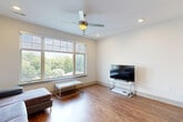 This thoughtfully designed one-bedroom, one-bathroom residence in Winston-Salem, NC offers a functional and modern living experience across a single floor. The open-concept layout seamlessly connects the living room and kitchen, creating an airy, cohesive space filled with natural light from large multi-pane windows. Rich hardwood-style flooring flows throughout the main living areas, complemented by neutral white walls and recessed lighting. A ceiling fan in the living room adds both comfort and style.

The kitchen is outfitted with dark cabinetry, granite-style countertops, a full suite of black appliances including a range, microwave, dishwasher, and refrigerator, and a peninsula that provides additional prep and dining space with pendant lighting above.

The spacious bedroom features plush carpeting, ample room for a full furniture arrangement, and convenient access to both the closet and the dedicated laundry room, which houses a full-size side-by-side washer and dryer with overhead shelving.

The bathroom includes a clean, all-white tub-shower combination with built-in shelving and brushed nickel fixtures. Throughout the unit, clean lines, recessed lighting, and a neutral palette create a bright, modern ambiance well-suited for comfortable everyday living.