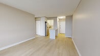 Located at 1101 Rue Rachel in Montréal's vibrant Plateau-Mont-Royal neighbourhood, this one-bedroom, one-bathroom unit offers a clean, modern aesthetic throughout its single-floor layout. Light-toned hardwood flooring runs continuously across all living areas, creating a bright and cohesive feel.

The open-concept living and dining area flows seamlessly into the kitchen, which features white flat-panel cabinetry, a subway tile backsplash, light quartz countertops, stainless steel appliances, and a central island that doubles as a casual dining or prep space. A closet with mirrored sliding doors adds practical storage near the entry.

The bedroom is generously proportioned and benefits from floor-to-ceiling windows that frame sweeping panoramic views of the Montréal cityscape. A sliding door provides access to a balcony, further enhancing the connection to the surrounding urban landscape. Baseboard heating units are present throughout, ensuring comfort year-round.

The bathroom is finished with neutral floor tiles, full-height wall tiles surrounding the soaker tub and shower combination, and clean white fixtures. The overall palette of warm beige walls, white trim, and light flooring gives the unit a bright, airy ambiance suited to modern urban living.