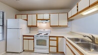 This well-appointed 1-bedroom, 1-bathroom unit is thoughtfully designed across a single floor, offering a comfortable and functional living experience. The open living area features wood-look plank flooring, soaring vaulted ceilings, and a ceiling fan, creating a bright and airy atmosphere. A classic fireplace serves as a focal point in the living room, which also includes a sliding glass door leading to a private balcony with outdoor views.

The galley-style kitchen is outfitted with rich dark cabinetry, granite countertops, stainless steel appliances including an electric range and refrigerator, a built-in dishwasher, a deep stainless steel sink, and a stylish pendant light fixture overhead — providing both functionality and visual appeal.

The bedroom offers plush carpeted flooring, neutral tones, and a spacious walk-in closet with built-in wire shelving for ample storage. The full bathroom continues the design consistency with a dark wood vanity, granite countertop, a large mirror, and a shower/tub combination.

A dedicated laundry area houses a full-size washer and dryer along with additional wire shelving, adding everyday convenience. Throughout the unit, a neutral color palette and clean finishes contribute to a cohesive, move-in-ready aesthetic.
