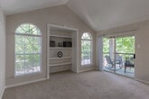 Located at 2330 Montgomery Park Blvd in Conroe, Texas, this single-floor residence blends functional design with comfortable living spaces throughout. The living room is a standout feature, boasting soaring vaulted ceilings, built-in white shelving, and an abundance of natural light through arched and standard windows. A sliding glass door opens directly to a private balcony, offering pleasant outdoor views and a seamless indoor-outdoor connection. Plush carpeting flows through the living areas and bedrooms, contributing to the home's warm and inviting ambiance. The kitchen is well-appointed with granite-style countertops, gray cabinetry, and recessed lighting beneath a vaulted ceiling, with an arched window that further brightens the space. The bedrooms are generously sized, each featuring ceiling fans, carpeted floors, and ample natural light from windows fitted with blinds. One bedroom includes access to an adjoining room, offering added versatility. The bathroom is clean and functional, featuring a full soaking tub with tiled surround and hardwood-style flooring. Tile flooring in the entryway transitions smoothly to the carpeted living areas, while neutral wall tones throughout create a cohesive and understated aesthetic ideal for a variety of interior styles.