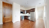 Located at 233 Lake Ave in the heart of Saratoga Springs, NY, this well-appointed 2-bedroom, 2-bathroom residence offers a thoughtfully designed single-floor layout. Rich hardwood flooring flows throughout the main living areas and kitchen, lending warmth and continuity to the space. The kitchen is outfitted with dark espresso cabinetry, stainless steel appliances including a refrigerator, range, microwave, and dishwasher, complemented by light countertops and recessed lighting overhead. Natural light enters generously through wood-framed windows dressed with blinds, visible across the living and bedroom areas. Both bedrooms feature soft neutral carpeting and are equipped with multiple closets, providing generous storage. The primary bedroom is a comfortable, well-proportioned retreat. Both bathrooms are finished with marble-style tile flooring, white vanity cabinetry, stone countertops, and gold-toned fixtures, conveying a clean and polished aesthetic. One bathroom also includes a glass-enclosed shower and additional wall-mounted storage cabinetry. A hallway connects the rooms efficiently within the compact but functional floor plan. The overall ambiance is bright, neutral, and move-in ready, offering a refined living experience in a sought-after Saratoga Springs location.