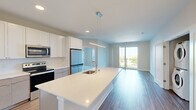 This well-appointed 3-bedroom, 2-bathroom residence is thoughtfully designed with a modern aesthetic and an open-concept layout that promotes a seamless flow between living spaces. The kitchen serves as a central hub, featuring a large quartz-topped island with an integrated sink, white shaker cabinetry, stainless steel appliances including a refrigerator, range, and microwave, and warm wood-look flooring that extends into the living area. Pendant lighting above the island adds a contemporary touch. The living area opens directly to a balcony through sliding glass doors, allowing abundant natural light and outdoor views to fill the space.

The expansive primary bedroom offers generous proportions, wood-look flooring, balcony access, and a dedicated closet, providing a comfortable private retreat. Additional bedrooms feature soft carpeting and large windows that frame pleasant outdoor views. Two well-designed bathrooms serve the residence — one featuring a dual-sink vanity with quartz countertops and a glass-enclosed walk-in shower, the other with a single vanity and a full tub-shower combination. Both bathrooms include wood-look flooring and clean, neutral finishes. Two closets provide ample storage throughout the home. The overall design presents a bright, clean, and functional living environment.
