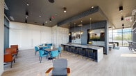 Located at 2109 S Wabash Ave in Chicago's South Loop neighborhood, this contemporary amenity lounge is a thoughtfully designed communal space that blends industrial aesthetics with upscale finishes. The open floor plan is anchored by an expansive bar island topped with sleek stone countertops, lined with navy and gold bar stools and illuminated by a striking cluster of globe and dome pendant lights in brushed gold. Behind the bar, textured tile walls and built-in cabinetry create a sophisticated backdrop, complete with a large mounted display screen.

Raw concrete accent walls punctuate the interior, adding an industrial edge that contrasts beautifully with the light wood-plank flooring. A generous dining and lounge area features rich wood tables surrounded by teal upholstered chairs, offering flexible seating arrangements. Floor-to-ceiling glass walls and sliding doors on one side flood the space with natural light while framing panoramic views of the surrounding Chicago skyline and neighborhood rooftops. These doors open directly onto a spacious outdoor terrace furnished with seating, turf, and high-top tables.

A dedicated game zone features wood-paneled ceilings, a teal bench, arcade machines, and casual seating, adding a playful element to the space. A refined wet bar alcove with mosaic tile detailing and framed mirror niches rounds out the amenities, creating a well-appointed, multi-functional gathering space.