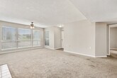 This single-story home offers a well-organized layout across three bedrooms and two full bathrooms. The spacious living room serves as the heart of the home, featuring a tile-surround fireplace, ceiling fan, plush wall-to-wall carpeting, and large windows that flood the space with natural light and provide outdoor views. A glass door opens from the living room, adding to the bright and airy atmosphere.

The galley-style kitchen is equipped with dark wood cabinetry, a double-basin sink, a range, and black appliances including a refrigerator and dishwasher, all set above wood-look flooring. A pass-through counter connects the kitchen to the main living area for easy flow.

Each bedroom is carpeted and includes built-in closet storage. The primary bedroom features a spacious walk-in closet with wire shelving systems for organization. Additional bedrooms offer standard reach-in closets with hanging rods. A decorative pendant light fixture adds a stylish touch to one of the secondary bedrooms.

The primary bathroom includes a dual-sink vanity with dark wood cabinetry, a large mirror, and wood-look flooring. The secondary bathroom features a single-sink vanity and a full shower-tub combination with accessibility grab bars. Both bathrooms are finished with bright vanity lighting. The home also includes dedicated hallways, an entrance area, and a separate closet for additional storage.