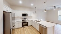 Located at 900 3rd St SE in Cedar Rapids, Iowa, this one-bedroom, one-bathroom unit offers a thoughtfully designed single-floor layout with a clean, modern aesthetic. Light wood-look flooring flows through the main living areas, complemented by neutral warm-toned walls that create a bright and welcoming atmosphere throughout.

The kitchen is a standout feature, equipped with white shaker-style cabinetry, crisp white countertops, and a full suite of stainless steel appliances including a refrigerator, electric range, built-in microwave, and dishwasher. A peninsula with a double undermount sink adds functional counter space, while brushed nickel pendant lights overhead lend a contemporary touch. Recessed lighting illuminates the workspace efficiently.

The bedroom offers comfortable proportions, plush carpeting, a ceiling fan, and a large window that invites natural light and outside views. A closet provides convenient storage directly off the room.

The bathroom is finished in a clean, neutral palette with wood-look flooring, a white vanity with a single sink, a full tub and shower combination, and brushed nickel fixtures throughout. The overall design of the unit emphasizes functionality and modern simplicity, making it a well-appointed and move-in ready space in Cedar Rapids.
