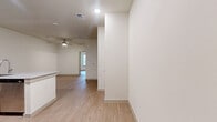 This efficiently designed one-bedroom, one-bathroom unit offers a thoughtfully planned single-floor layout with a clean, modern aesthetic throughout. Light wood-tone flooring flows seamlessly across every room, creating a cohesive and airy feel complemented by crisp white walls and recessed lighting.

The open-concept kitchen is a standout feature, equipped with stainless steel appliances including a refrigerator, electric range, and over-the-range microwave. Rich dark-toned cabinetry pairs with granite countertops, and a peninsula with an integrated sink provides additional prep space and casual seating opportunities, making it the natural hub of the living area. A ceiling fan overhead enhances comfort in the connected living space, which also benefits from natural light filtering in through a window.

The bedroom is a comfortable, well-proportioned retreat featuring a ceiling fan, a window with blinds for natural light and privacy, and direct access to a generously sized walk-in closet outfitted with dual hanging rods and built-in shelving. A second closet provides additional storage flexibility.

The bathroom mirrors the design language of the kitchen, featuring a dark wood vanity with granite countertop, a framed mirror, and wood-tone flooring. A dedicated laundry area rounds out this practical and polished unit.