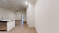 This efficiently designed one-bedroom, one-bathroom unit offers a thoughtfully planned single-floor layout with a clean, modern aesthetic throughout. Light wood-tone flooring flows seamlessly across every room, creating a cohesive and airy feel complemented by crisp white walls and recessed lighting.

The open-concept kitchen is a standout feature, equipped with stainless steel appliances including a refrigerator, electric range, and over-the-range microwave. Rich dark-toned cabinetry pairs with granite countertops, and a peninsula with an integrated sink provides additional prep space and casual seating opportunities, making it the natural hub of the living area. A ceiling fan overhead enhances comfort in the connected living space, which also benefits from natural light filtering in through a window.

The bedroom is a comfortable, well-proportioned retreat featuring a ceiling fan, a window with blinds for natural light and privacy, and direct access to a generously sized walk-in closet outfitted with dual hanging rods and built-in shelving. A second closet provides additional storage flexibility.

The bathroom mirrors the design language of the kitchen, featuring a dark wood vanity with granite countertop, a framed mirror, and wood-tone flooring. A dedicated laundry area rounds out this practical and polished unit.