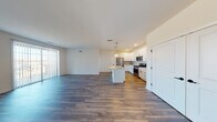 Located at 1S601 S Finley Rd in Lombard, Illinois, this single-floor unit offers a thoughtfully designed open-concept layout that seamlessly connects the living area and kitchen. The expansive main living space is finished with wide-plank hardwood-style flooring in a rich, warm tone that extends throughout the unit, lending a cohesive and contemporary feel.

The kitchen is a standout feature, outfitted with crisp white shaker-style cabinetry accented by matte black hardware, light granite countertops, and a full suite of stainless steel appliances including a gas range, built-in microwave, and French door refrigerator. A central island with an undermount sink and pendant lighting above serves as a functional and stylish focal point, ideal for both meal preparation and casual dining. Recessed lighting and a subtle tile backsplash complete the kitchen's modern aesthetic.

The living area is generously proportioned, bathed in natural light from sliding glass doors that open to a balcony, offering pleasant outdoor views. The neutral white walls and clean lines throughout create a bright, airy atmosphere.

The bathroom continues the design language of the space, featuring white cabinetry, granite countertops, a framed mirror, and matte black fixtures, complemented by hardwood-style flooring at the entry transitioning to plush carpeting in adjacent rooms.