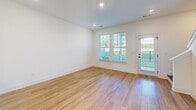 Located at 122 Pine Breeze Way in Greenville, SC, this two-story home offers a bright, modern aesthetic defined by crisp white walls, light hardwood flooring, and an abundance of natural light throughout. The main level features a well-appointed kitchen outfitted with stainless steel appliances—including a refrigerator, range, built-in microwave, and dishwasher—complemented by dark granite countertops and white shaker-style cabinetry with black hardware. The living and dining areas are open and airy, with recessed lighting, large windows, and a door providing direct outdoor access and views of the surrounding greenery. Bedrooms across both floors are generously sized, each benefiting from natural light filtered through plantation shutters or slatted blinds, ceiling fans, and closet storage. The bathrooms are finished in a clean, contemporary style: one features a dual-sink vanity with white countertops, dark bronze fixtures, and hardwood flooring, while another includes a tub-shower combination and a single vanity with ample cabinet storage. A central staircase connects the two floors, as seen in the dollhouse overview, which reveals a well-organized and efficiently designed layout. The home's consistent use of neutral tones and quality finishes creates a cohesive and inviting atmosphere throughout.