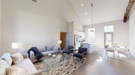 Located within Farrell Communities at Islip in Central Islip, NY, this thoughtfully designed single-floor home combines modern architecture with a bright, open layout. The centerpiece of the home is a dramatic vaulted ceiling that soars above the open-concept living, dining, and kitchen area, creating a sense of grandeur and airiness. Large windows invite abundant natural light, enhancing the warm wood-tone flooring that extends throughout the main living spaces.

The kitchen is outfitted with crisp white shaker cabinetry, stainless steel appliances including a gas range and built-in microwave, and a sleek peninsula with countertop seating — ideal for casual dining or entertaining. The living area features generous space for seating arrangements and flows seamlessly into a secondary sitting area, also bathed in natural light from a tall multi-pane window with views of the surrounding community.

The bedrooms offer a serene retreat, with clean neutral tones, ample closet space with sliding doors, and restful natural light. The bathroom is finished with elegant marble-style tile flooring, a gray shaker vanity, and a well-lit mirror. Additional areas provide flexible storage and display space. Throughout, the home maintains a cohesive, contemporary aesthetic defined by neutral palettes, clean lines, and quality finishes.
