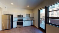 Located at 131 Ionia Ave SW in downtown Grand Rapids, Michigan, this single-floor unit offers a contemporary design with consistent, modern finishes throughout. The open kitchen serves as a central feature, equipped with a full suite of stainless steel appliances including a range, over-the-range microwave, dishwasher, and refrigerator. White cabinetry with dark hardware pairs with dark granite countertops and a white subway tile backsplash to create a clean, polished aesthetic. Wood-look plank flooring flows uniformly throughout the entire unit, contributing to a cohesive feel.

The living area receives generous natural light through large black-framed windows and a glass door that opens directly onto a private balcony, offering views of the surrounding urban streetscape. The bedroom areas include well-sized closets with built-in shelving, and the paneled white interior doors add a refined architectural touch.

The bathroom is finished to a high standard, featuring a dark granite vanity countertop, white cabinetry, a walk-in shower, and a backlit frameless mirror that enhances both functionality and ambiance. Recessed lighting throughout the unit further complements the modern, clean design of this downtown Grand Rapids residence.