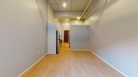 Located at 2225 E Lake St in Minneapolis, MN, this thoughtfully updated single-floor unit offers a clean, modern aesthetic throughout. The open living area is anchored by light hardwood flooring, exposed ductwork overhead, and elevated ceilings that lend an industrial-loft character to the space. A sliding glass door floods the room with natural light and opens directly to a private ground-level patio, providing an inviting indoor-outdoor connection.

The galley-style kitchen is efficiently designed and well-appointed, featuring stainless steel appliances including a refrigerator, electric range, and over-the-range microwave. White shaker-style cabinetry with matte black hardware pairs with granite-look countertops and a stainless steel sink, giving the kitchen a polished, contemporary feel. Track lighting above adds both function and visual interest.

The bathroom is clean and simply appointed, with a full soaking tub and shower combination, white surround, and matte black fixtures that echo the hardware choices found throughout the unit. Light tile flooring completes the crisp, neutral palette.

Throughout the space, a consistent design language of white walls, light flooring, and black accents creates a cohesive and modern atmosphere. The unit's layout maximizes functionality while maintaining an open, airy feel well-suited to urban living in the vibrant East Lake Street corridor.