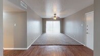 Located at 1744 Belt Line Rd in Garland, Texas, this single-story unit offers a practical and comfortable layout with a variety of functional finishes throughout. The open living area features wood-look flooring and transitions seamlessly into a carpeted zone, with a ceiling fan overhead and a large sliding glass door fitted with vertical blinds that allows natural light to fill the space. An adjacent dining or secondary living area also features wood-look flooring and connects directly to the kitchen via a pass-through bar counter.

The kitchen is equipped with warm-toned wood cabinetry, granite countertops, and black appliances including a refrigerator and dishwasher, complemented by textured walls and wood-look flooring.

The bedrooms are carpeted and each includes a ceiling fan with light fixture. The primary bedroom features mirrored closet doors and direct access to an en-suite bathroom. Additional bedrooms offer natural light through blinded windows and closet access. Both bathrooms are finished with granite-topped vanities, dark-framed mirrors, wood-look flooring, and tiled tub-shower combinations, providing a cohesive and clean aesthetic throughout the unit.