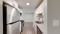 Located at 16W571 Mockingbird Ln in Willowbrook, IL, this single-floor, 2-bedroom, 1-bathroom home offers a well-organized layout that maximizes comfort and functionality. The galley-style kitchen is a standout feature, showcasing crisp white shaker cabinetry, granite countertops, a stainless steel sink with a modern faucet, and a full suite of stainless steel appliances including a gas range, microwave, refrigerator, and dishwasher. Light wood-tone flooring runs throughout the kitchen and common areas, contributing to a clean, contemporary aesthetic. The spacious living room is finished with neutral-toned carpet and clean white trim, providing a versatile canvas for various furniture arrangements. Both bedrooms are carpeted and bathed in natural light from sliding or standard windows that offer views of the surrounding greenery. The primary bedroom is generously sized and includes a large double-door closet for ample storage. The bathroom features a gray vanity with a white countertop, a wall-mounted mirror, and wood-tone flooring, all accented with brushed nickel hardware. A dedicated laundry area adds everyday convenience. The home's neutral color palette and updated finishes create a cohesive, move-in-ready atmosphere throughout.