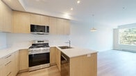 Located at 2900 Tillicum Road in Victoria, BC, this well-appointed one-bedroom, one-bathroom unit offers a thoughtfully designed layout across a single floor. The open-concept living and kitchen area sets a modern tone, featuring light wood cabinetry, stainless steel appliances including a gas range, microwave, and refrigerator, and a sleek peninsula with a white quartz countertop and undermount sink. Warm hardwood flooring flows throughout the main living areas, complementing the clean, neutral palette of the walls and recessed lighting overhead. The bedroom is a bright, serene retreat, benefiting from a large picture window that frames views of mature evergreen trees and connects the interior to the natural surroundings outside. A baseboard heater ensures year-round comfort. The bathroom is finished with contemporary details, including a light wood vanity with a white countertop, stone-look tile flooring, and a sliding glass shower enclosure. In-suite laundry adds a practical convenience to the unit. The overall ambiance is clean, modern, and efficient — an ideal space for those seeking functional urban living in a well-designed setting.