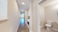 Located at 323 Taughannock Blvd in Ithaca, NY, this single-floor unit offers a thoughtfully designed layout that maximizes its compact footprint. The open living and kitchen area serves as the heart of the space, showcasing polished concrete floors that lend a contemporary, industrial character throughout. The kitchen is well-appointed with crisp white shaker cabinetry, a classic subway tile backsplash, stainless steel appliances including a range, microwave, dishwasher, and refrigerator, and a stainless steel sink. A distinctive sliding barn door with frosted glass panels provides both a stylish architectural element and functional room division. Recessed lighting and a ceiling fan keep the space bright and comfortable, while multiple windows allow natural light to fill the open living area, creating an airy ambiance. A wall-mounted mini-split unit ensures efficient climate control year-round. The bathroom features a fully tiled walk-in shower with subway tile walls, a glass enclosure, and brushed nickel fixtures, delivering a clean and modern aesthetic. The hallway connects the spaces efficiently, rounding out this well-organized and contemporary unit near the scenic waterfront of Cayuga Lake.