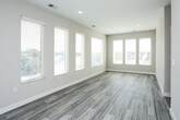 This single-floor residence presents a thoughtfully designed layout with a cohesive contemporary aesthetic throughout. The open-concept kitchen and living area serves as the heart of the space, where wood-look plank flooring extends across the common areas, complementing the warm, neutral palette of the walls. A row of large windows floods the living area with abundant natural light and provides views of the surrounding neighborhood.

The kitchen is well-appointed with dark walnut-toned cabinetry, stainless steel appliances including a refrigerator, electric range, and over-the-range microwave, and a light quartz peninsula countertop with an integrated sink. Pendant lighting accents the peninsula, adding a refined touch.

The bedrooms are comfortably sized and carpeted in a neutral tone, each featuring windows that allow natural light and outdoor views. The two bathrooms maintain a consistent modern design, featuring dark wood-grain vanities with white quartz countertops, undermount sinks, chrome fixtures, and wood-look tile flooring. One bathroom includes a wall-mounted mirror with overhead lighting. The overall design is clean, modern, and functional, with a consistent material palette unifying the entire space.