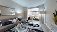 Located at 100 Trumbull Street in Hartford, CT, this residence at Spectra Park delivers a thoughtfully designed single-floor layout with modern finishes throughout. The living area is a standout space, anchored by large floor-to-ceiling windows that frame views of the Hartford cityscape, filling the room with abundant natural light. Light hardwood flooring, neutral taupe walls, and a clean, contemporary aesthetic create a welcoming and refined atmosphere. The kitchen features wood-toned cabinetry, dark stone countertops, a decorative patterned tile backsplash with under-cabinet lighting, and light-toned upper cabinets, combining both functionality and style. The bedroom is a serene retreat, carpeted for comfort, with natural light filtering through sheer window treatments and ample closet space. The bathroom is finished with stylish mosaic tile flooring in a grey-and-white pattern, a sleek open-frame vanity with a white countertop, and a backlit mirror, lending it a spa-inspired feel. Throughout the residence, the cohesive neutral color palette, quality finishes, and carefully considered design details come together to create a polished and comfortable urban living environment in the heart of downtown Hartford.