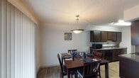 This single-story unit in Beaumont, Texas, offers a practical and comfortable layout across two bedrooms and one bathroom. The open-concept dining area flows naturally toward the kitchen, creating a connected and functional living space. A pendant light fixture hangs above the dining area, which features wood-style flooring and large vertical blinds that allow for natural light control. The kitchen is equipped with dark cabinetry, granite-style countertops, a double sink, and black appliances including a refrigerator, dishwasher, and microwave, with ample upper and lower cabinet storage.

The living room provides a relaxed, open feel with wood-style flooring, neutral walls, and a ceiling-height layout that keeps the space feeling airy. Both bedrooms are carpeted and include ceiling fans with light fixtures, windows for natural light, and closets with bifold doors offering convenient storage. The full bathroom features a shower-tub combination with tile surround and wood-style flooring, completing the unit's cohesive design. Throughout the space, textured ceilings and neutral tones create a clean, understated aesthetic well-suited for everyday living.
