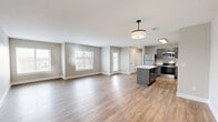 Located at 1218 Boone Aire Rd in Florence, Kentucky, this well-appointed one-bedroom, one-bathroom unit offers a thoughtfully designed layout across a single floor. The open-concept living and kitchen area serves as the heart of the home, featuring warm wood-look luxury vinyl plank flooring that flows seamlessly throughout. The kitchen is a standout, equipped with dark espresso-toned cabinetry, crisp white quartz countertops, a central island with additional storage, stainless steel appliances including a refrigerator, range, microwave, and dishwasher, and a sleek matte black faucet. The spacious living area is bathed in natural light from multiple windows with views of the surrounding landscape. The bedroom offers plush wall-to-wall carpeting, natural light from a large window, and access to multiple closets — five in total throughout the unit — providing exceptional storage, including a generously sized walk-in closet with wire shelving. The bathroom features a full tub-shower combination with white tile surround, matte black fixtures, and wood-look flooring. A private balcony extends the living space outdoors. Neutral warm-toned walls and clean white trim create a cohesive, modern aesthetic throughout.