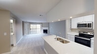 Located at 1203 Deerfield Pkwy in Buffalo Grove, Illinois, this single-floor residence offers a well-designed open-concept layout that seamlessly connects the kitchen and living areas. The living room is a standout space, featuring plush neutral carpeting, soft gray walls, and a classic white-mantled fireplace that serves as a natural focal point. A sliding glass door floods the room with natural light and provides direct access to an outdoor balcony with views of the surrounding landscape.

The kitchen is thoughtfully appointed with white cabinetry, light stone-look countertops, a double undermount sink set into a peninsula, and stainless steel appliances including a refrigerator and range. Wood-look flooring runs through the kitchen, which also provides convenient access to utility and storage areas.

The bedrooms are carpeted and finished in warm neutral tones, offering comfortable, well-proportioned spaces with good natural light from standard windows. Two bathrooms serve the unit; one features a tub-shower combination with tile surround, wood-look flooring, a white vanity, and built-in storage cabinetry. The second bathroom mirrors a similarly clean, functional aesthetic with a single-sink vanity and additional cabinet storage. The overall ambiance throughout is calm, neutral, and move-in ready.
