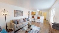 This thoughtfully designed 2-bedroom, 2-bathroom residence offers a functional and comfortable single-floor layout. The open-concept living area features warm wood-style flooring throughout, crisp white walls, and recessed lighting that creates a bright, welcoming atmosphere. The living room provides generous space for seating and entertaining, flowing seamlessly into the kitchen area.

The kitchen is equipped with warm honey-toned cabinetry, granite-style countertops, a dishwasher, electric range, and a breakfast bar with seating — ideal for casual dining. A hallway with wood-style flooring connects the main living areas to the private quarters.

Both bedrooms feature plush carpeting and ceiling fans with light fixtures. The primary bedroom is spacious, featuring dual windows that allow natural light to fill the room. The second bedroom also benefits from natural light through a large window, making it well-suited as a guest room or home office.

The two bathrooms are clean and functional. One includes a full tub and shower combination with white tile surround, while the other features a vanity with a wide mirror and ample counter space. The overall layout is practical and efficient, offering comfortable living across a well-appointed floor plan.