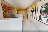 This 260 square foot facility in Irvine, California is a thoughtfully designed pet grooming space. The single-floor layout maximizes functionality in a compact area. Upon entry, glass doors flood the space with natural light, offering views of the surrounding greenery. The interior boasts a clean, modern aesthetic with cream-colored walls and floors, accented by vibrant red and orange tiled sections that add warmth and energy to the environment. A standout feature is the professional-grade stainless steel grooming station, complete with steps for easy pet access. The space is further enhanced by playful, oversized portraits of dogs, adding a touch of whimsy to the professional setting. Practical elements include recessed lighting, a circular mirror, and a sleek counter area. This well-equipped facility combines functionality with a welcoming atmosphere, catering to both the practical needs of pet grooming and the comfort of its furry clients.