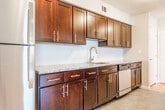 Located at 118 Sunrise Dr in Edison, NJ, this single-floor home offers a thoughtfully arranged layout with consistent design elements throughout. Gleaming hardwood flooring runs through the main living areas and bedrooms, reflecting natural light and lending warmth to each room.

The spacious living area is bright and open, featuring multiple windows with blinds that frame outdoor views of surrounding greenery. A sliding glass door connects to an adjacent space, while an elegant chandelier anchors the dining area nearby. A pass-through window opening connects the living area to the kitchen, enhancing the sense of flow between spaces.

The galley-style kitchen is well-appointed with dark espresso cabinetry, granite countertops, stainless steel appliances including a gas range, microwave, and refrigerator, and a stainless sink. The neutral tile flooring provides a clean contrast to the rich cabinetry.

The bedrooms are generously sized, each offering hardwood floors, neutral walls, and windows that allow ample natural light and outdoor views. One bedroom features a six-panel door opening to a walk-in closet area.

The bathroom is finished with dark vanity cabinetry, a white countertop, a large mirror, and tile flooring, complemented by a tub-shower combination. Overall, the home presents a clean, modern aesthetic with practical and comfortable living spaces.